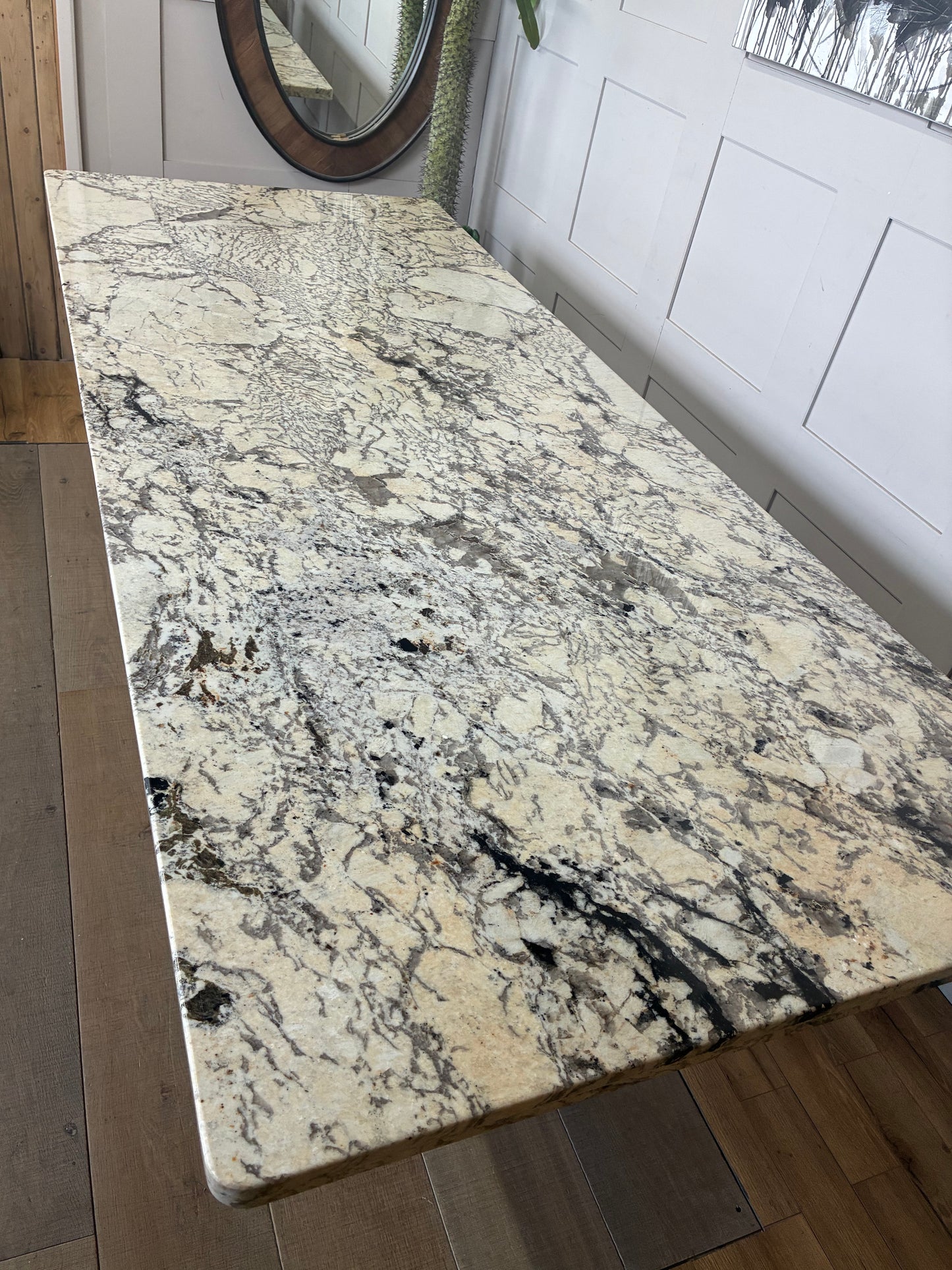A rectangular Anthropologie Renata dining table with a thick, polished white marble top. The table is supported by thick, cylindrical wooden legs featuring a vertical fluted texture and a warm oak finish.
