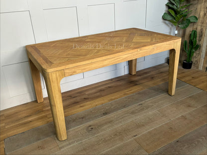"A rectangular dining table crafted from light-toned reclaimed solid teak wood, featuring a subtle marquetry-patterned tabletop and sturdy wooden legs