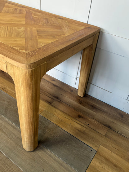 "A rectangular dining table crafted from light-toned reclaimed solid teak wood, featuring a subtle marquetry-patterned tabletop and sturdy wooden legs
