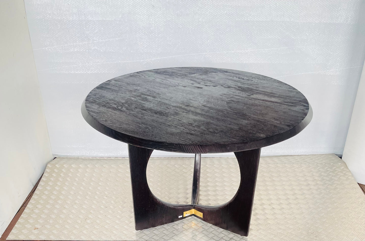 A round, black oak wood Anthropologie Iris dining table featuring a modern, sculptural silhouette with curved lines