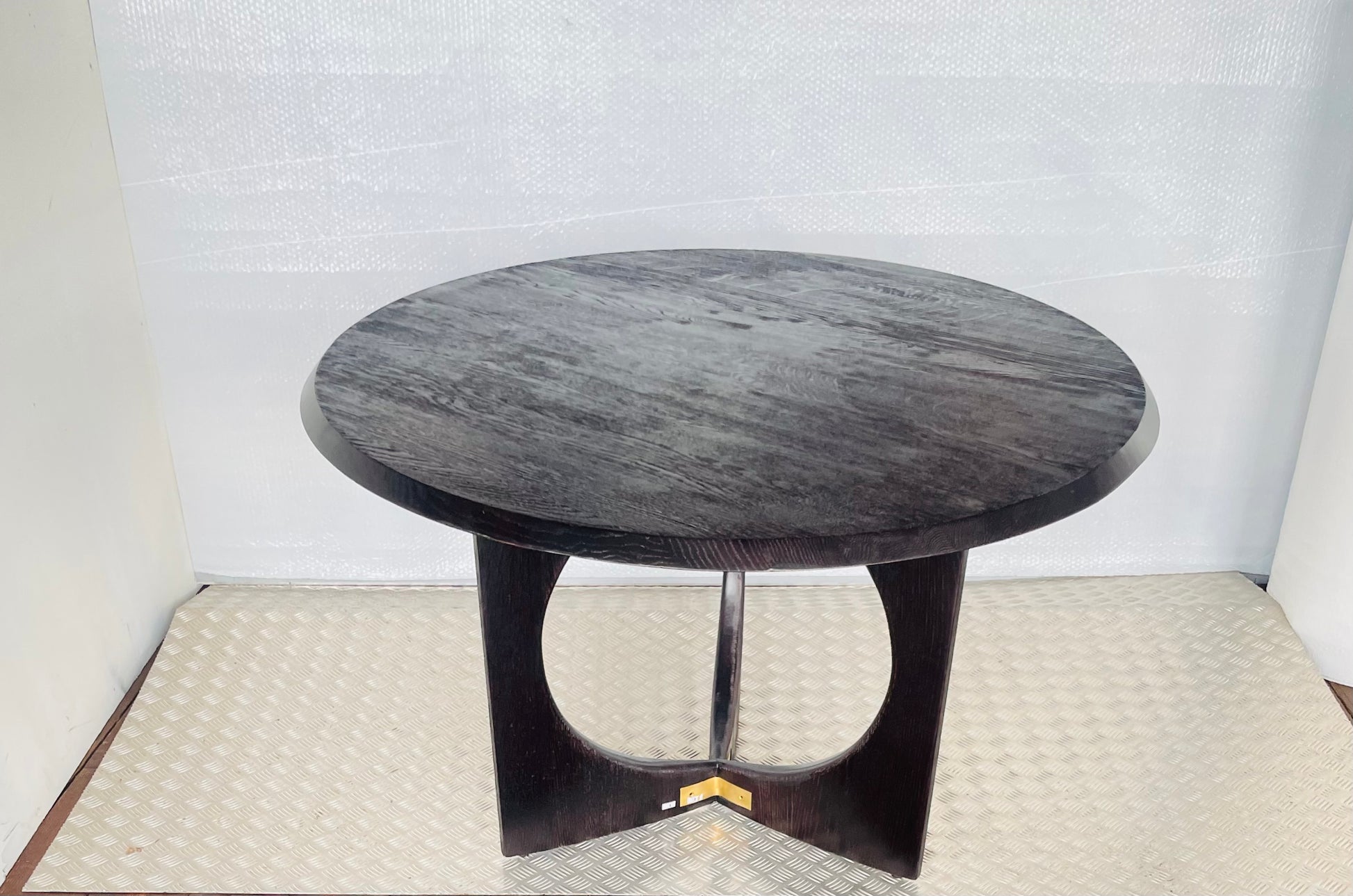 A round, black oak wood Anthropologie Iris dining table featuring a modern, sculptural silhouette with curved lines