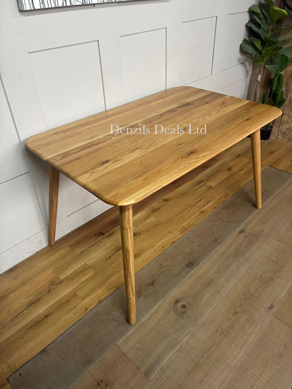 A round wooden dining table with a smooth solid oak top finished in a light bianco oil, supported by simple wooden legs