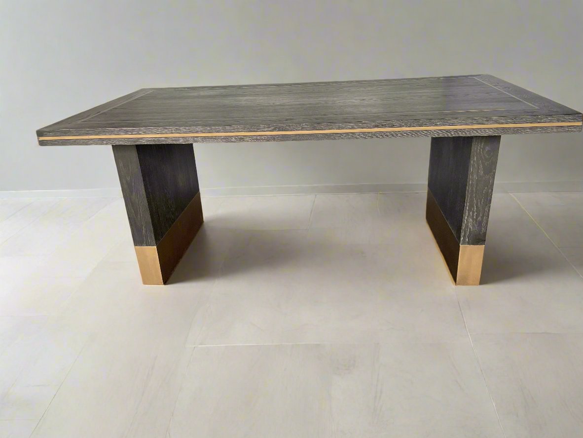 A small rectangular Richmond Interiors Hunter dining table featuring a black oak veneer tabletop with matte brushed gold metal legs and geometric corner inlay details. 