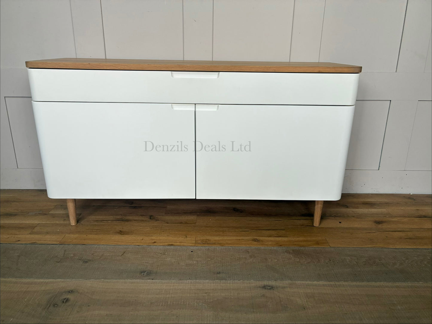 A styled living room featuring the white and oak Ebbe Gehl for John Lewis Mira sideboard positioned against a neutral wall, decorated with home accessories on its wooden top.
