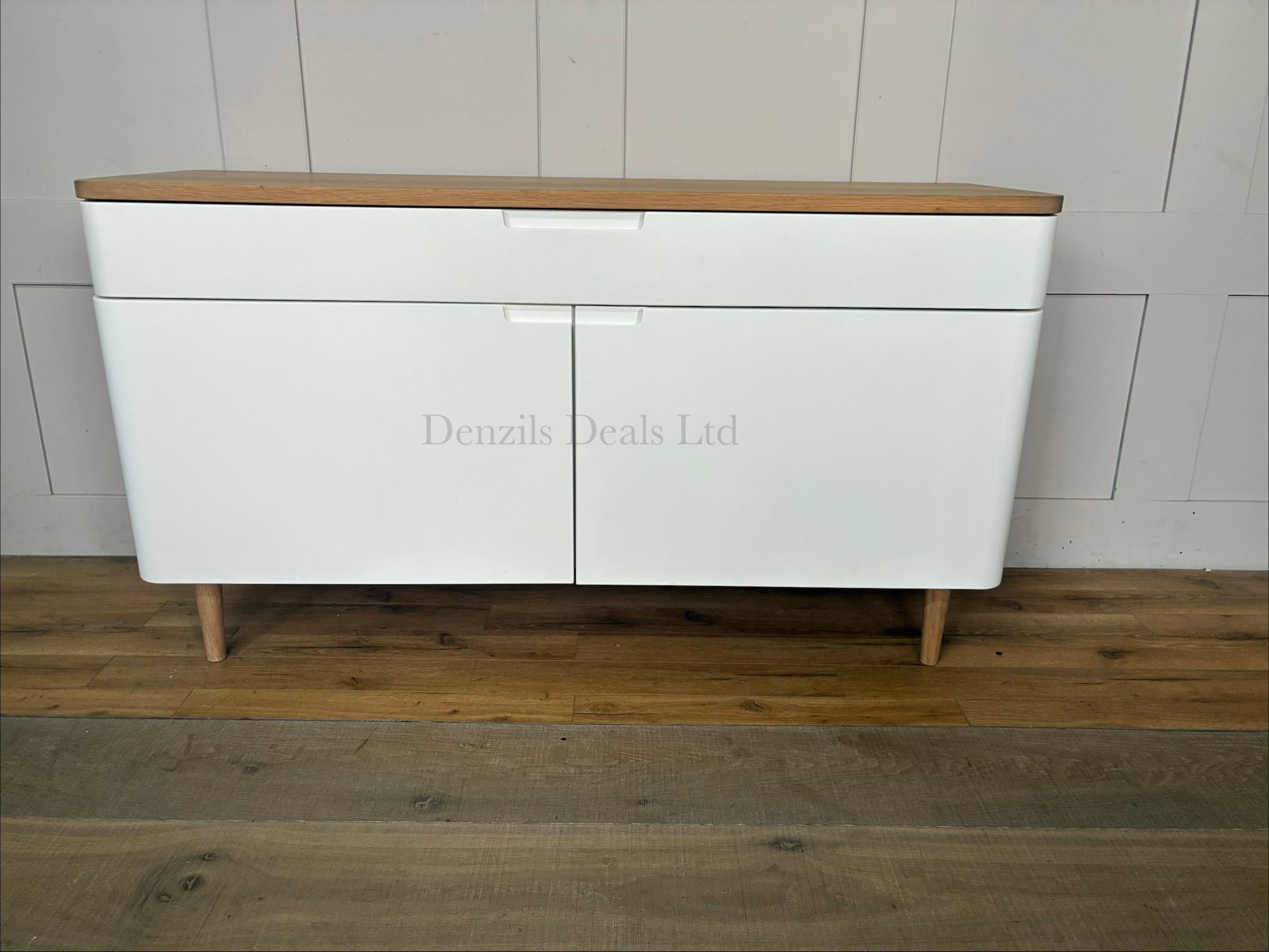A styled living room featuring the white and oak Ebbe Gehl for John Lewis Mira sideboard positioned against a neutral wall, decorated with home accessories on its wooden top.