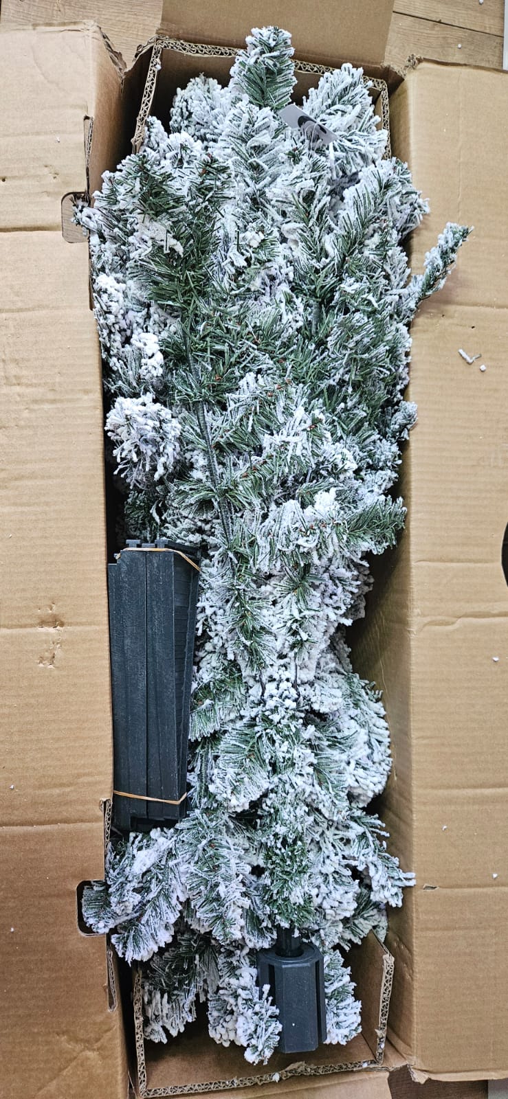 A traditional 6ft conical artificial spruce Christmas tree by M&S, featuring a full, dense silhouette with 527 tips coated in a thick layer of white faux snow, complete with a dark metal floor stand."