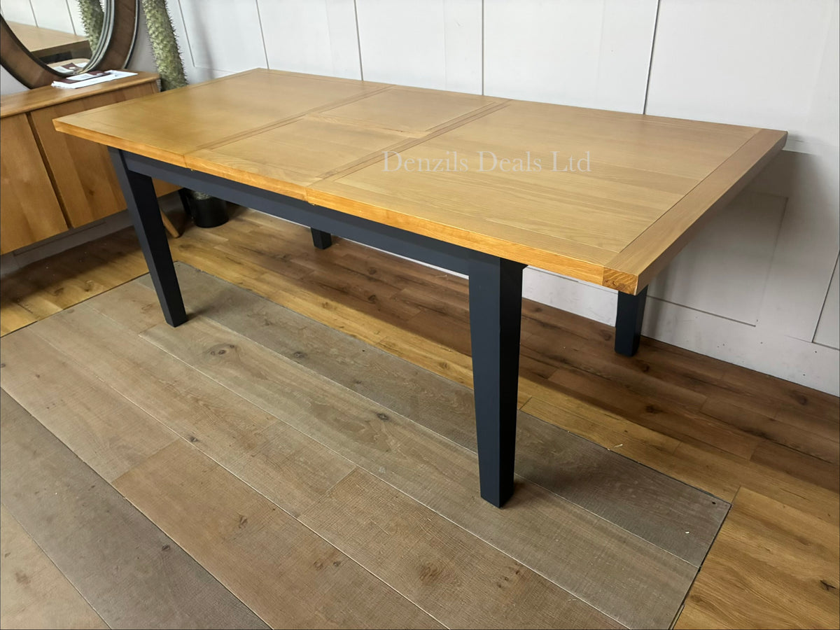 A traditional dining room featuring the DFS Country Living Maud navy extending dining table, showcasing its rustic dark blue frame and natural wood tabletop,