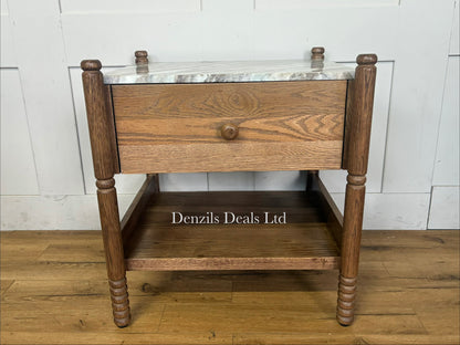 The Amelia Marble-Top Nightstand by Anthropologie features a smooth Toronto marble top, delicate spindled legs, an undermount shelf, and crafted oak woodgrain detailing.