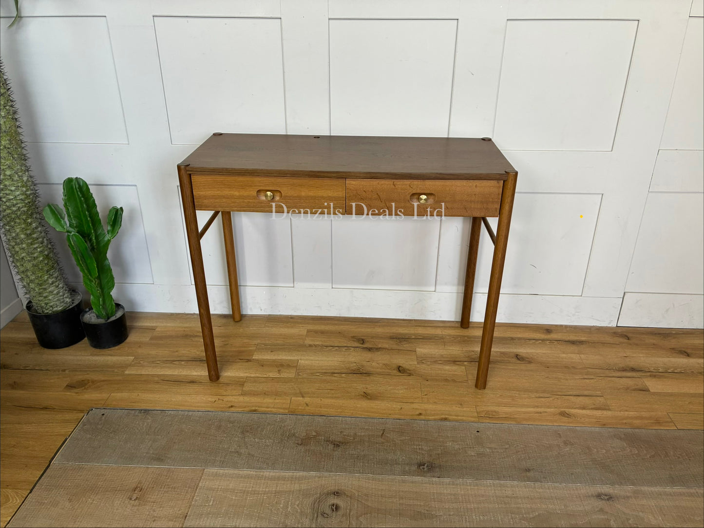 Anthropologie Bernadette Makeup Vanity crafted from solid oak with two drawers, and brass accents against a neutral wall