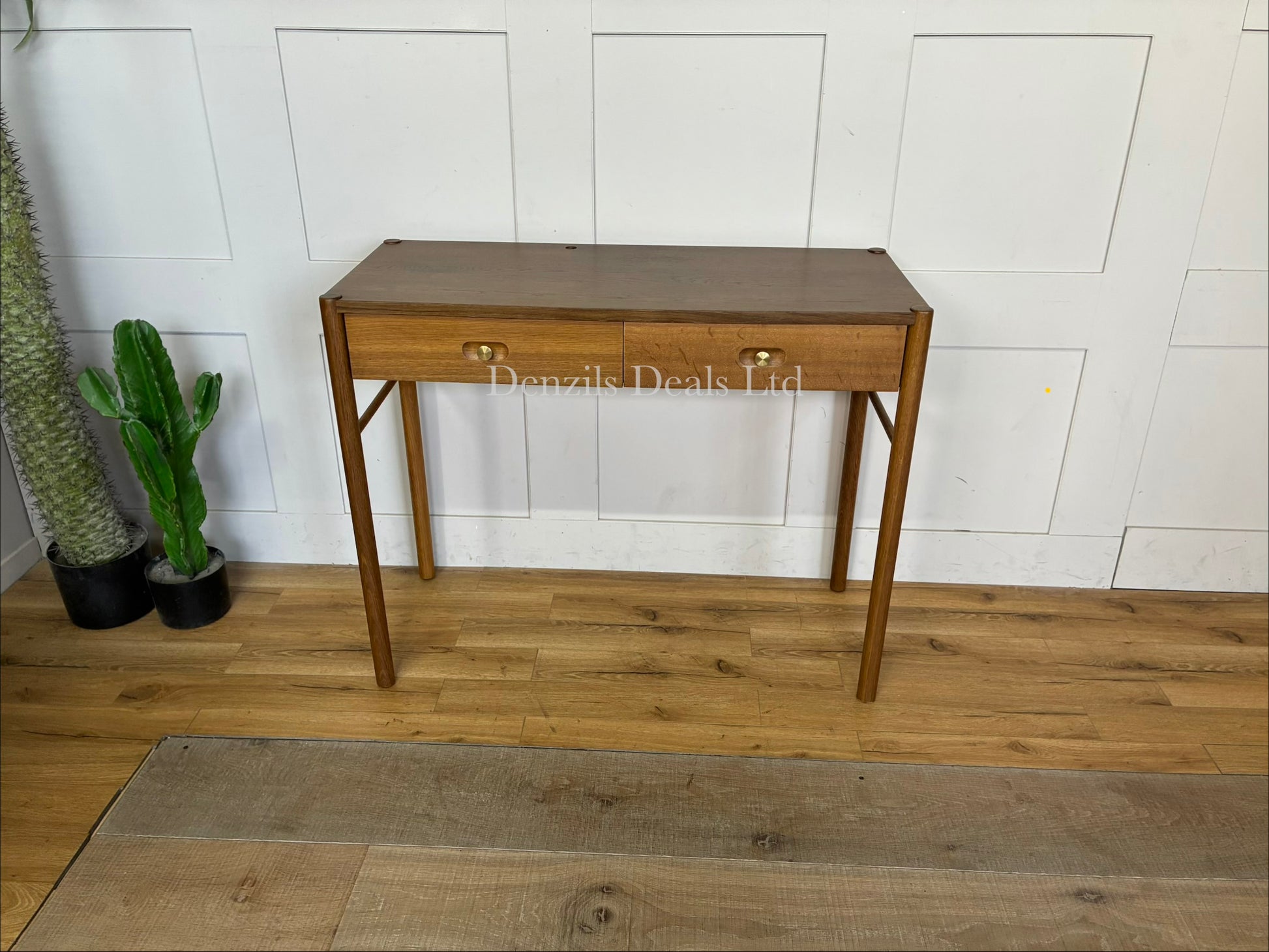 Anthropologie Bernadette Makeup Vanity crafted from solid oak with two drawers, and brass accents against a neutral wall
