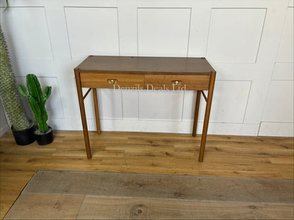 Anthropologie Bernadette Makeup Vanity crafted from solid oak with two drawers, and brass accents against a neutral wall