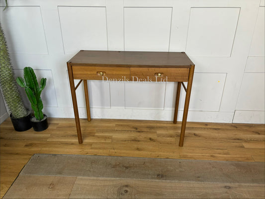 Anthropologie Bernadette Makeup Vanity crafted from solid oak with two drawers, and brass accents against a neutral wall