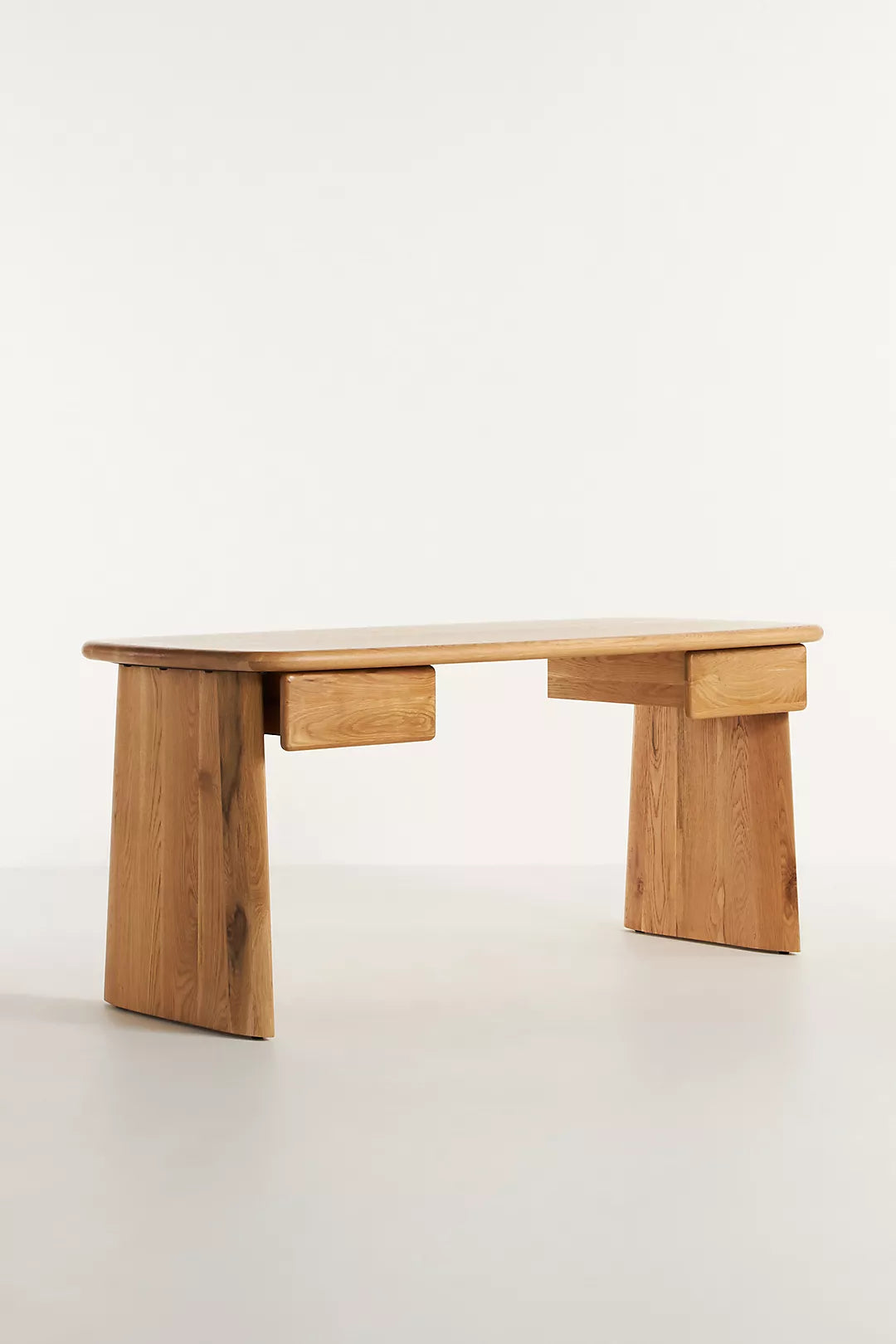 Anthropologie Kalle Sculptural Desk with natural oak wood grain and thick, rounded plank legs.