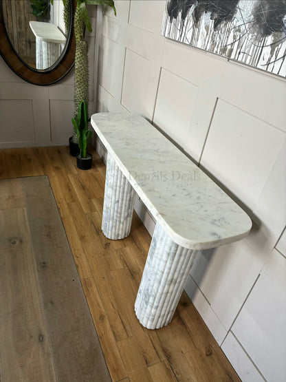 Modern minimalist Anthropologie Kanta marble console table with a thick, rectangular stone top. The table is supported by two wide, block-style legs featuring a deeply grooved, fluted texture that contrasts with the smooth, polished surface of the natural cream marble