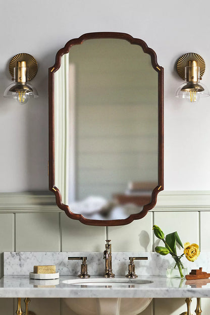Anthropologie Wall-mounted wooden medicine cabinet with a mirrored door, scalloped edge silhouette, and brass accents