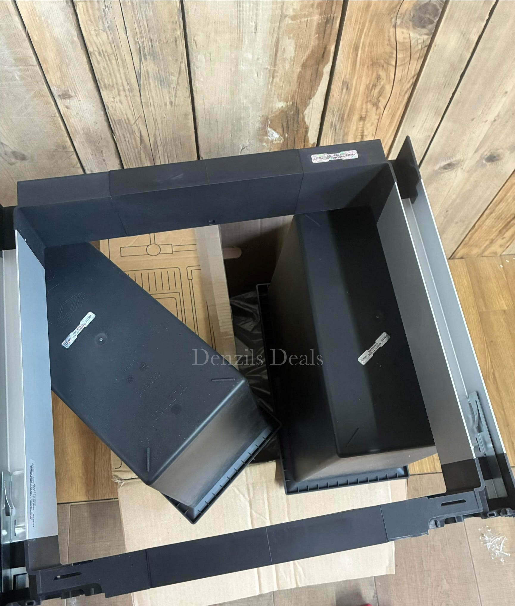 A BLANCO Select under-counter pull-out kitchen bin with two grey compartments, shown partially extended from a minimalist dark cabinet to reveal its 38-litre waste separation system. 