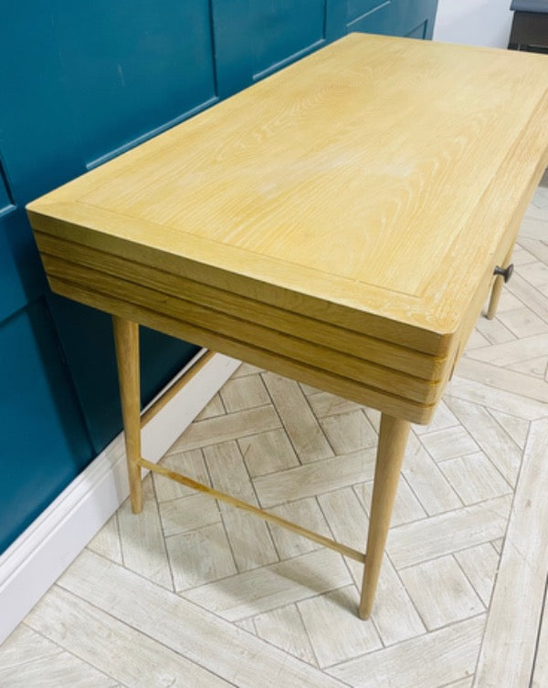 The Clever Bubba Desk by Loaf situated in a bedroom, featuring sturdy wooden legs and a pull-out drawer