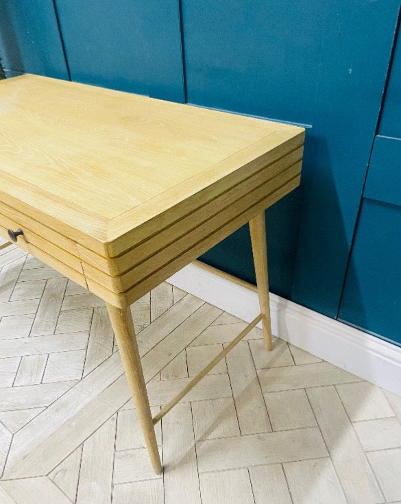 The Clever Bubba Desk by Loaf situated in a bedroom, featuring sturdy wooden legs and a pull-out drawer