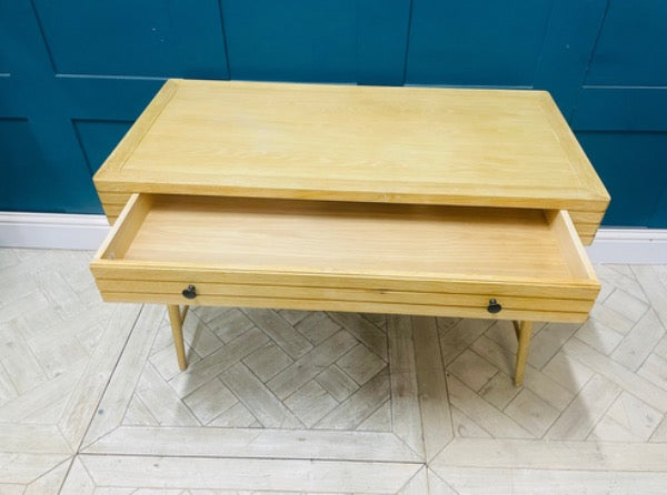 The Clever Bubba Desk by Loaf situated in a bedroom, featuring sturdy wooden legs and a pull-out drawer