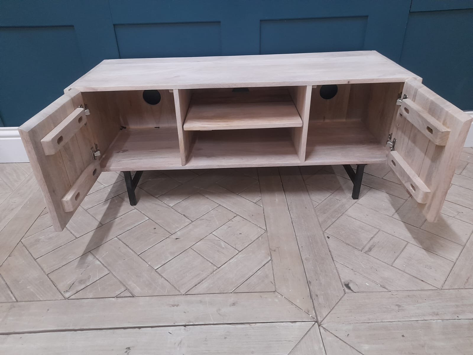Close-up of Aphra TV Stand showing light mango wood grain and black metal leg detail