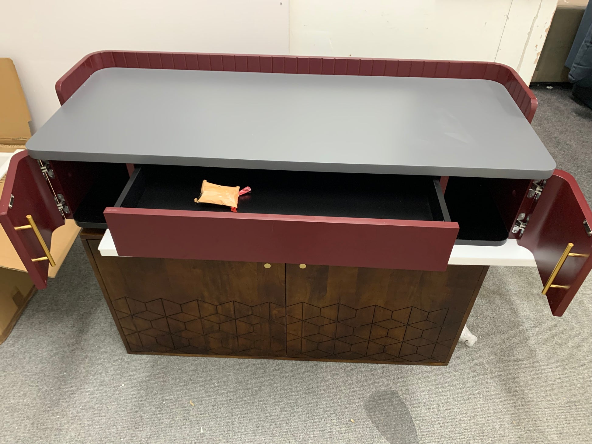 Close-up of the Lali wide desk showing polished brass handles on a matte mahogany red drawer