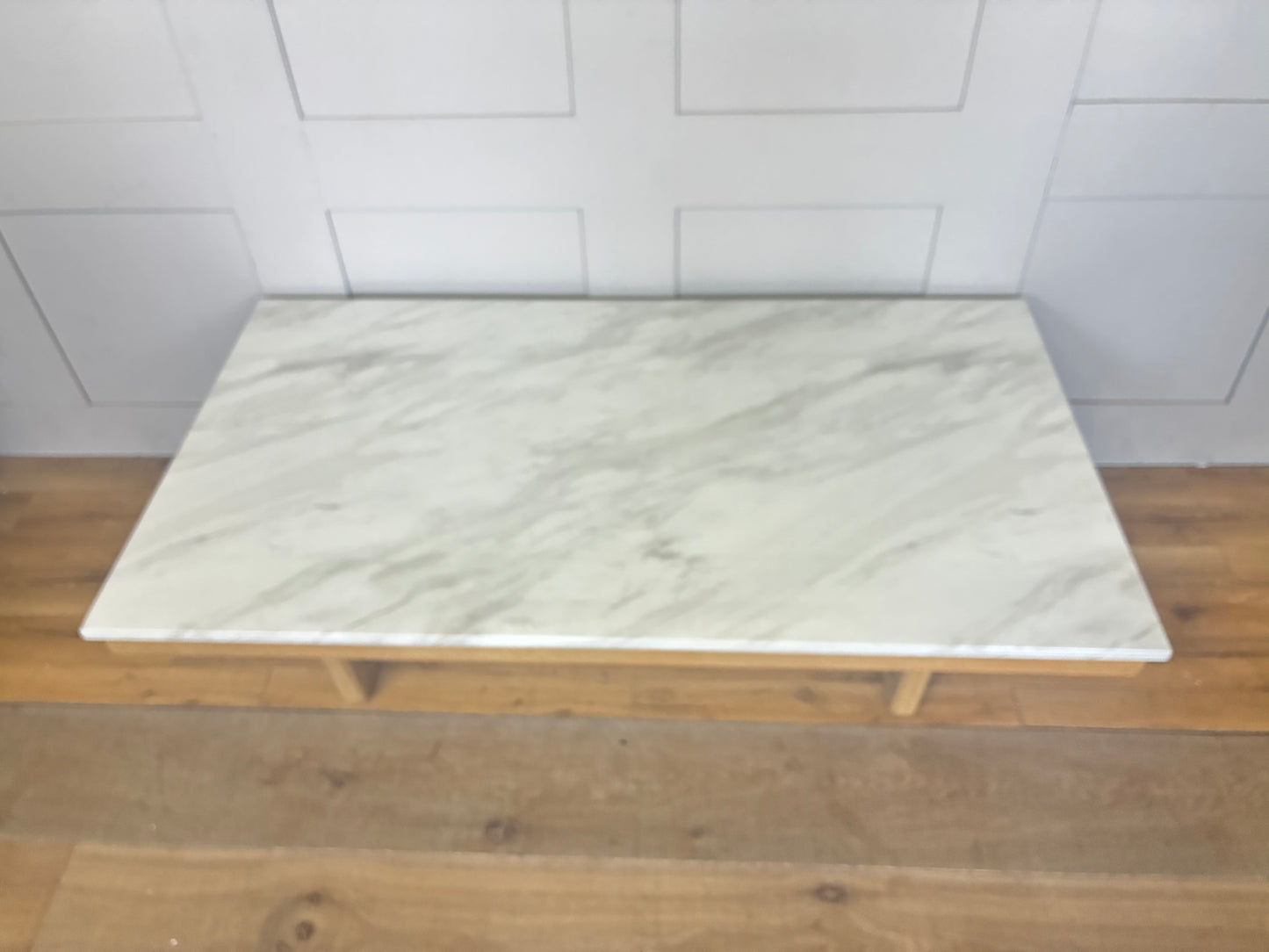 Close-up of the Nick Scali Carlina coffee table, highlighting the natural premium high-density white marble, mitred corner details, and rounded wooden legs."