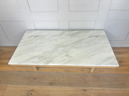 Close-up of the Nick Scali Carlina coffee table, highlighting the natural premium high-density white marble, mitred corner details, and rounded wooden legs."