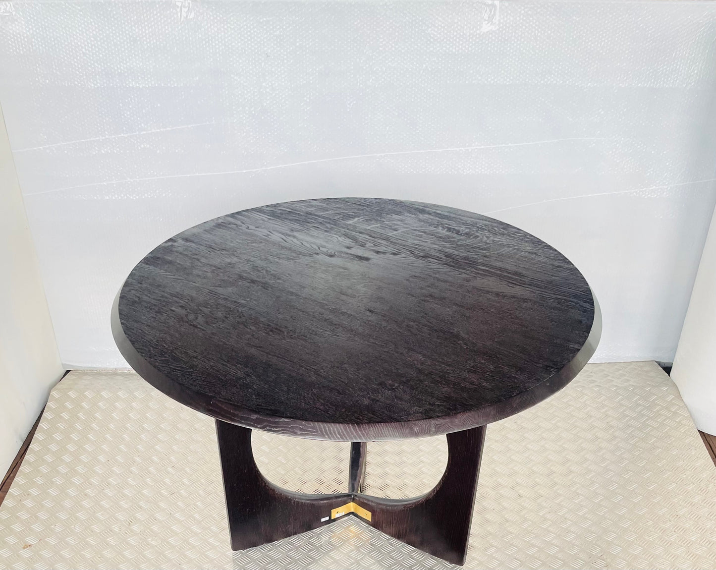 Close-up of the textured black oak wood grain and polished gold brass hardware accents on the Anthropologie Iris dining table edge."