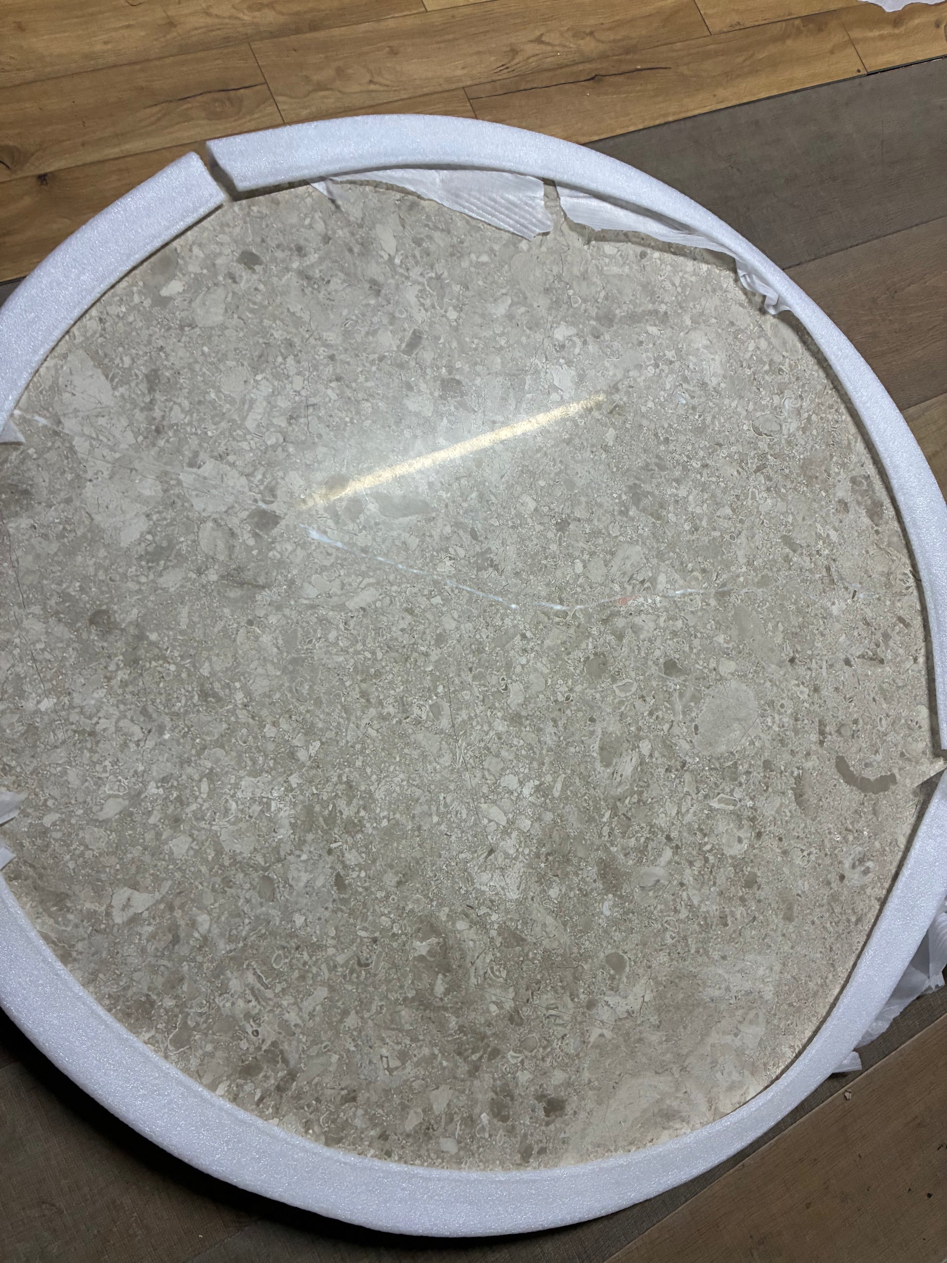 Close-up shot of the cream and beige veined marble surface and dark brown wooden base of the John Lewis Ritz dining table