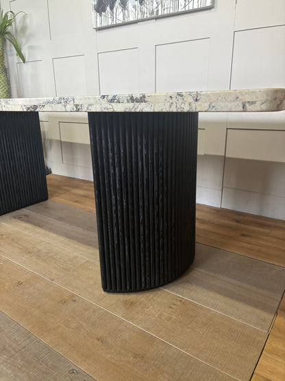 Close up view Anthropologie Renata dining table featuring a smooth marble top and rustic wooden fluted legs