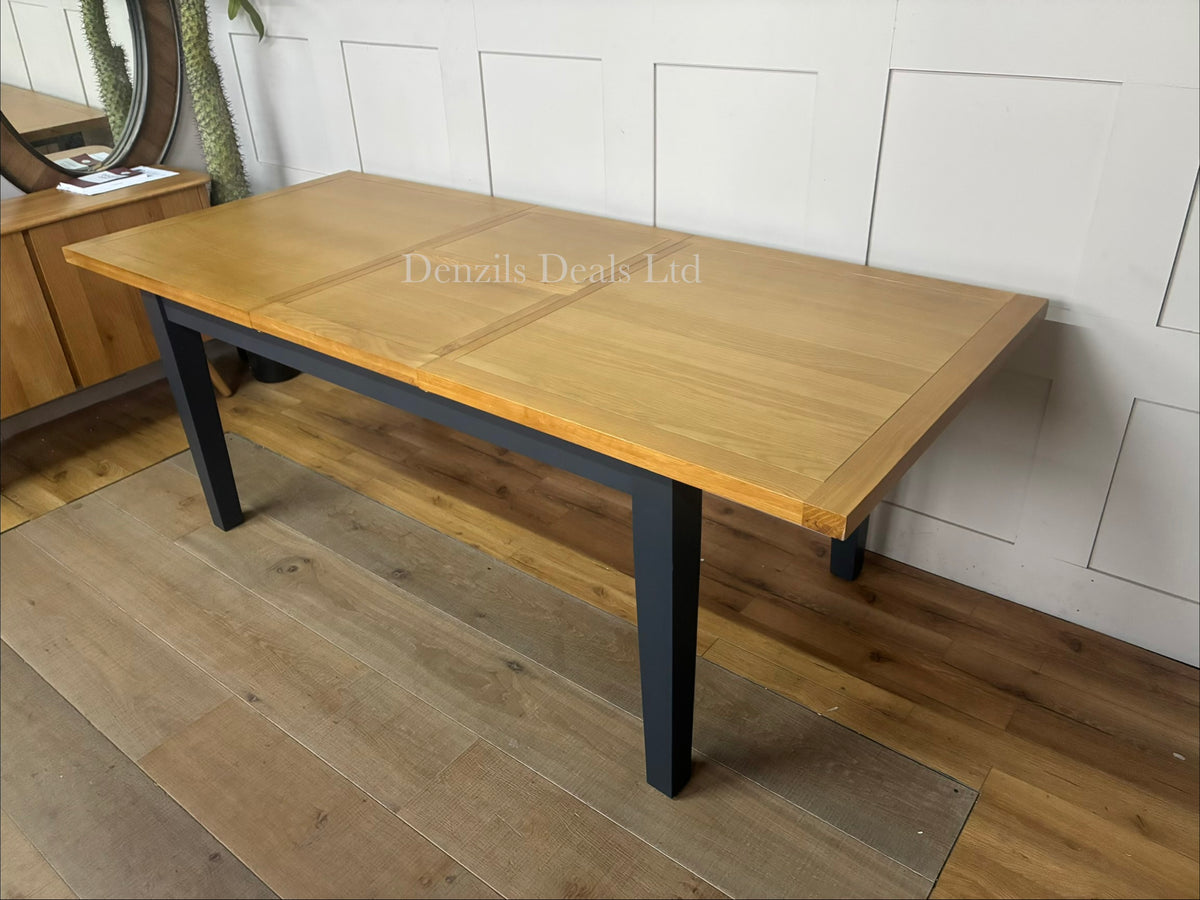 DFS Country Living Maud extending dining table featuring a deep navy blue painted wooden base and a natural, warm-toned solid oak top