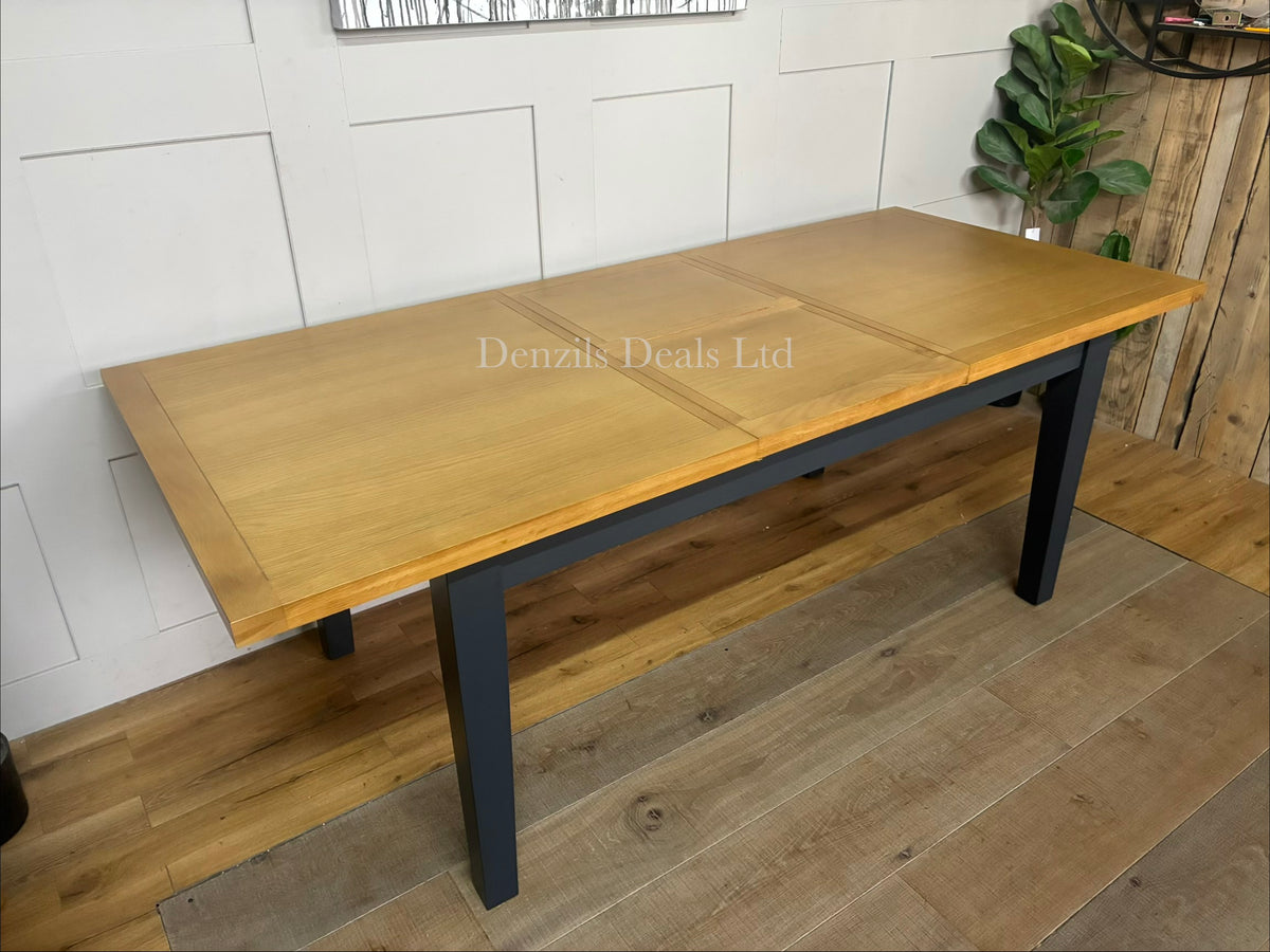 DFS Country Living Maud extending dining table featuring a deep navy blue painted wooden base and a natural, warm-toned solid oak top