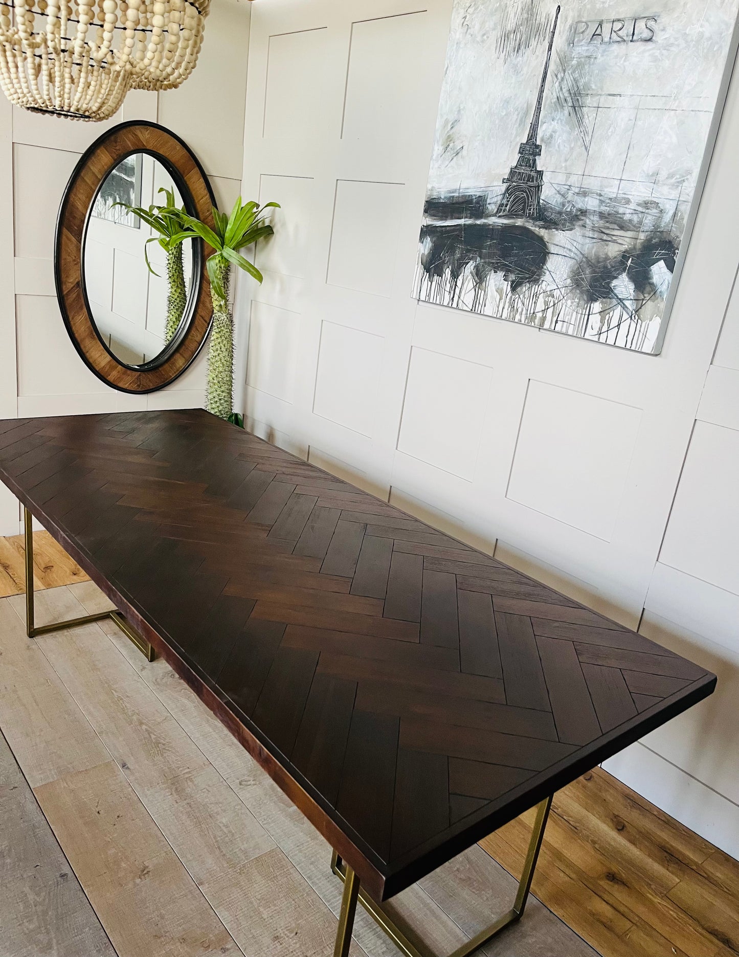 Dutchbone Class dining table with an inlaid dark acacia wood herringbone tabletop and slender, antique-brass metal legs."