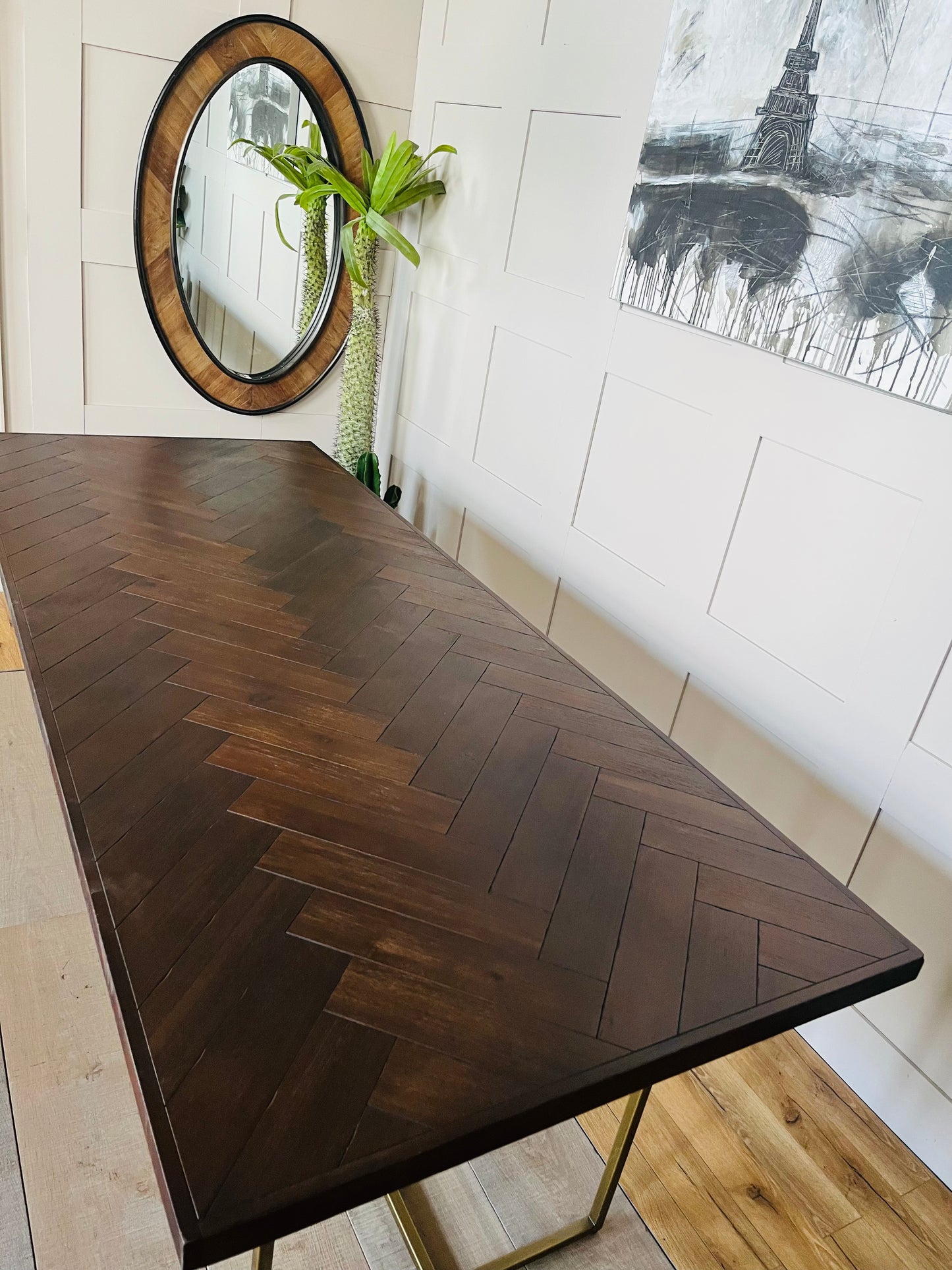 Dutchbone Class dining table with an inlaid dark acacia wood herringbone tabletop and slender, antique-brass metal legs."