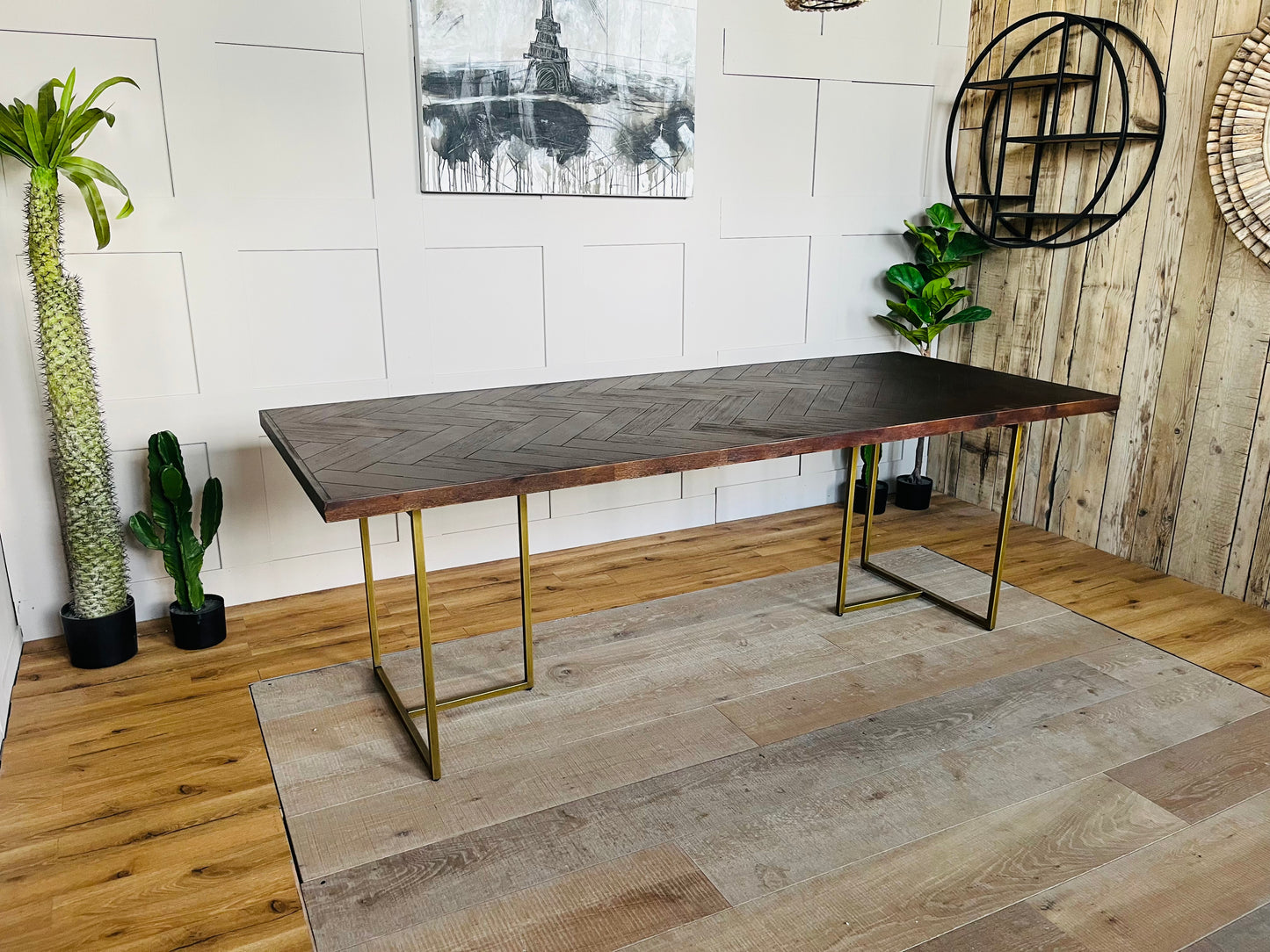 Rectangular Dutchbone Class dining table featuring a rich dark brown acacia wood top with an intricate herringbone pattern and a contrasting geometric brass-coated metal base."