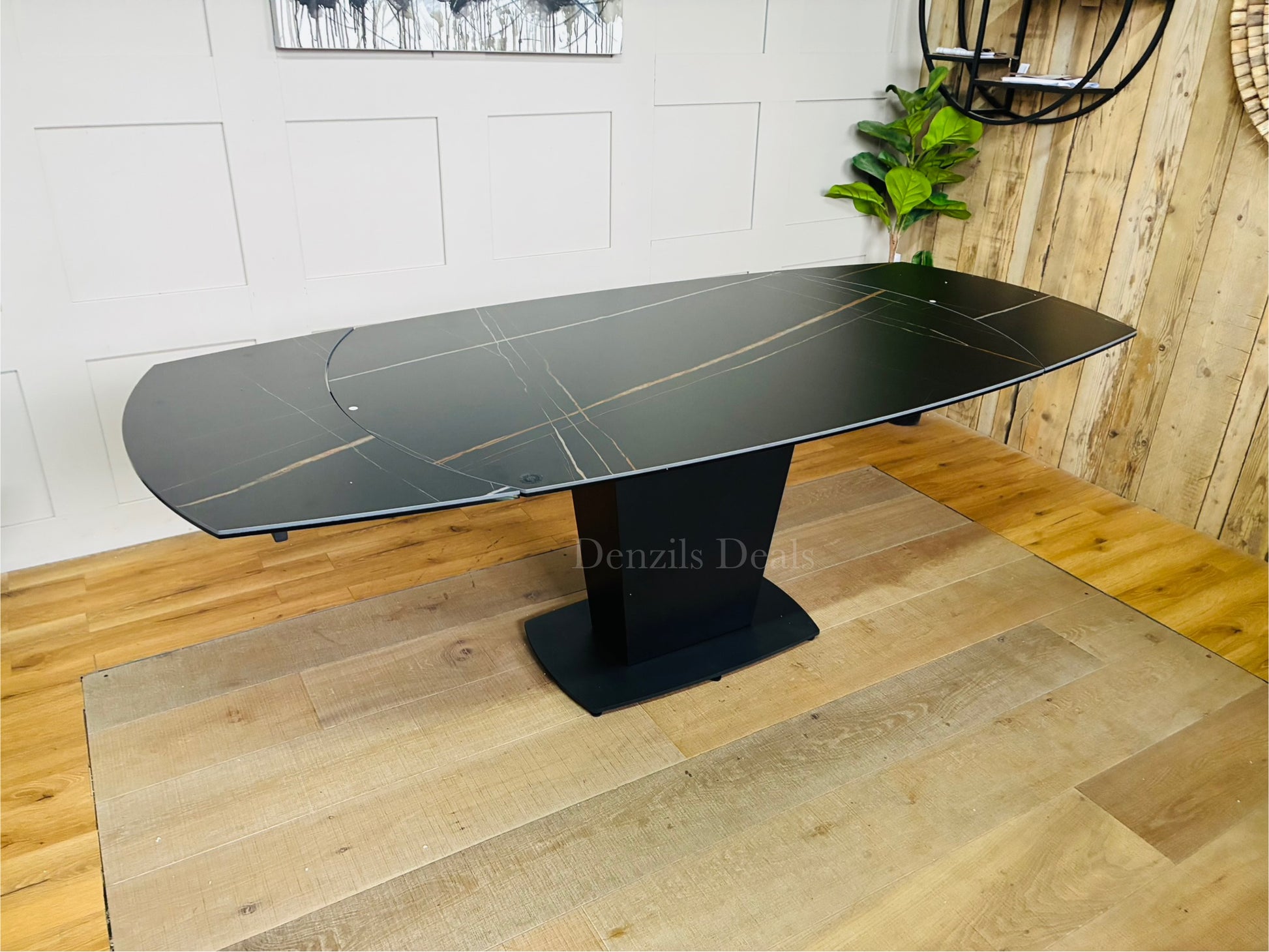 Dwell Tabula extending dining table shown in its unextended 150cm form, featuring a durable matte black ceramic tabletop with realistic marble veining, supported by a central black tulip base extends to 220cm