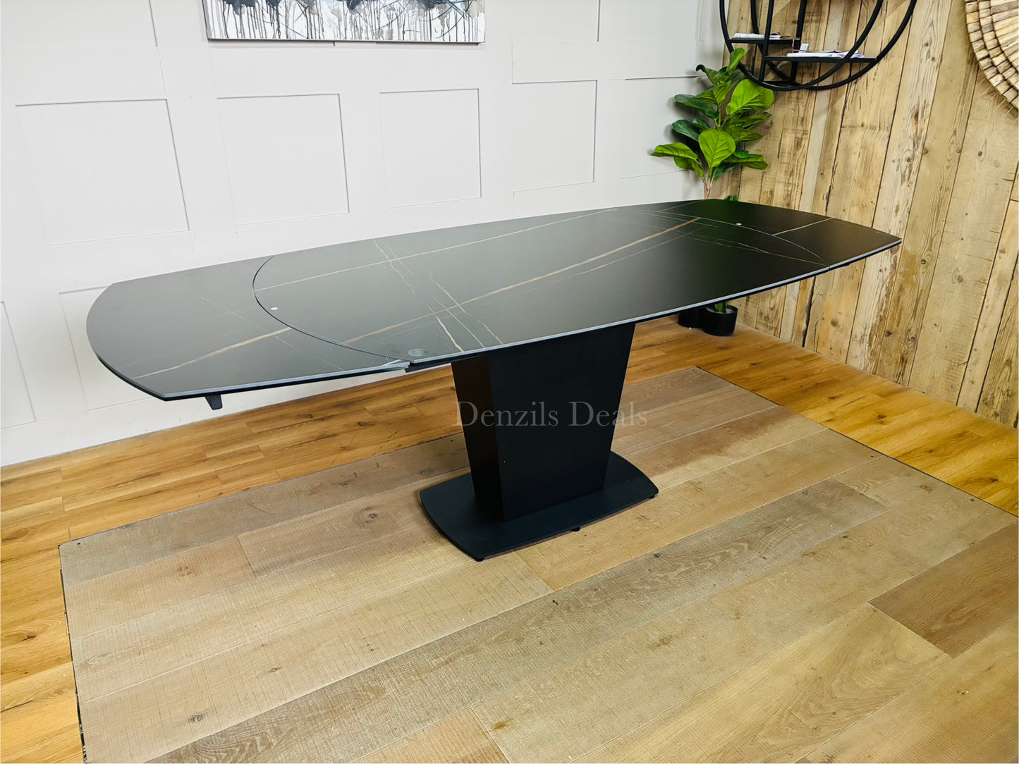 A black ceramic marble-effect dining table extending from 150cm to 220cm, showing the rotating mechanism that reveals side extension leaves to comfortably seat up to 8 people
