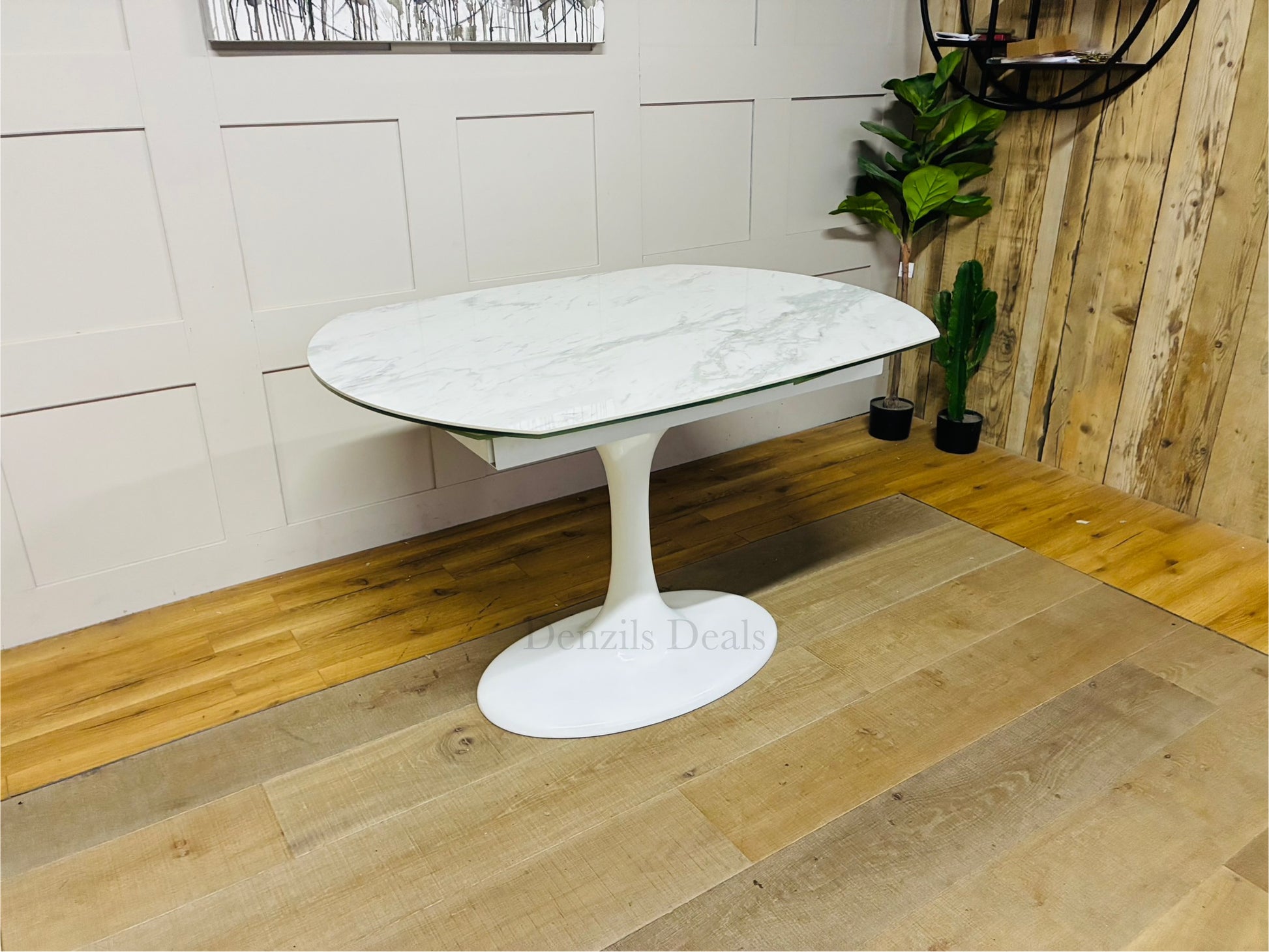 Round extending dining table from DFS featuring a white ceramic marble-effect top, curved edges, and a matching white fibreglass tulip base. Shown in a modern dining room setting."