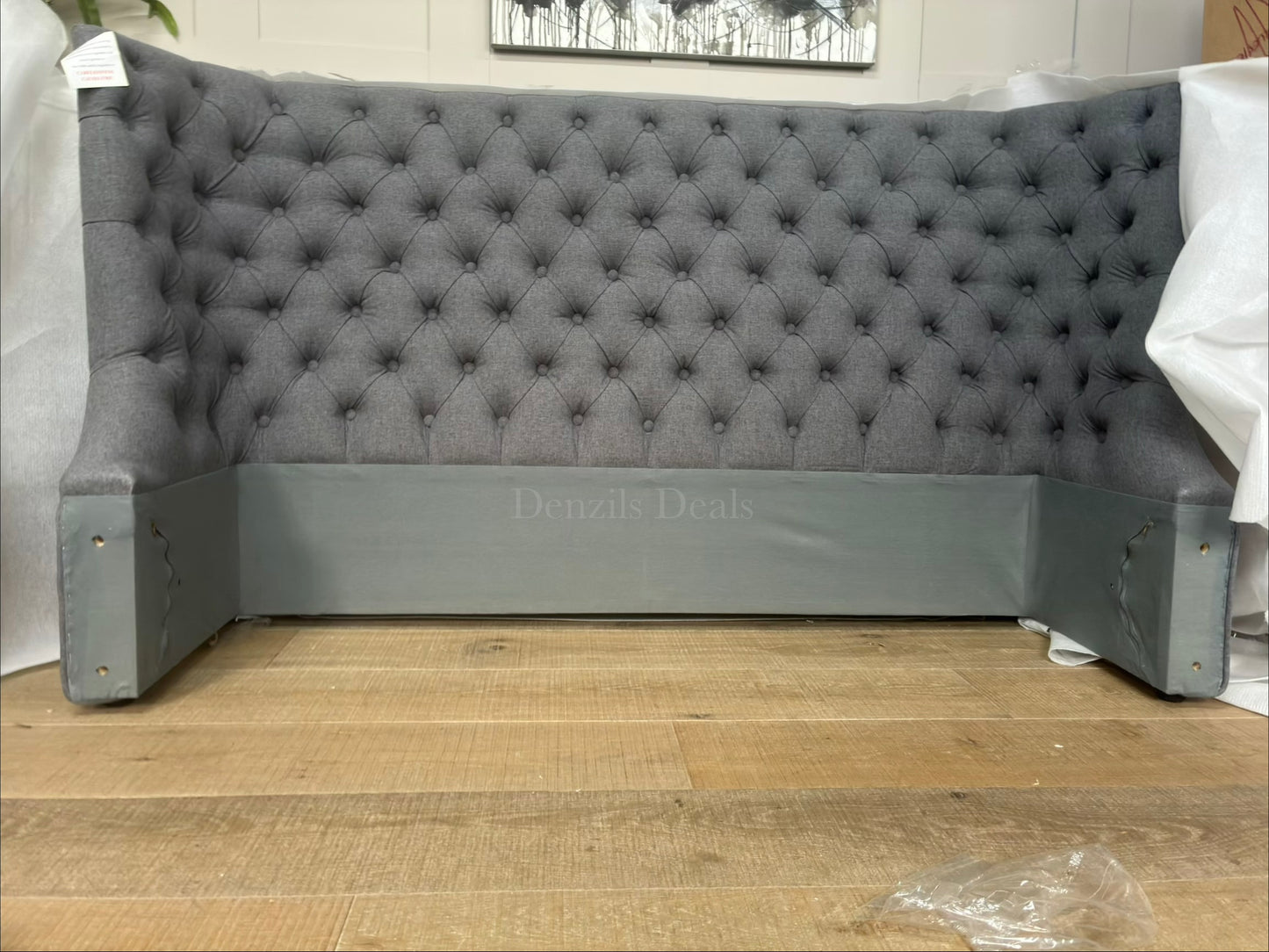 Elegant king size ottoman bed upholstered in grey fabric with a traditional buttoned headboard. Close up view on headboard 