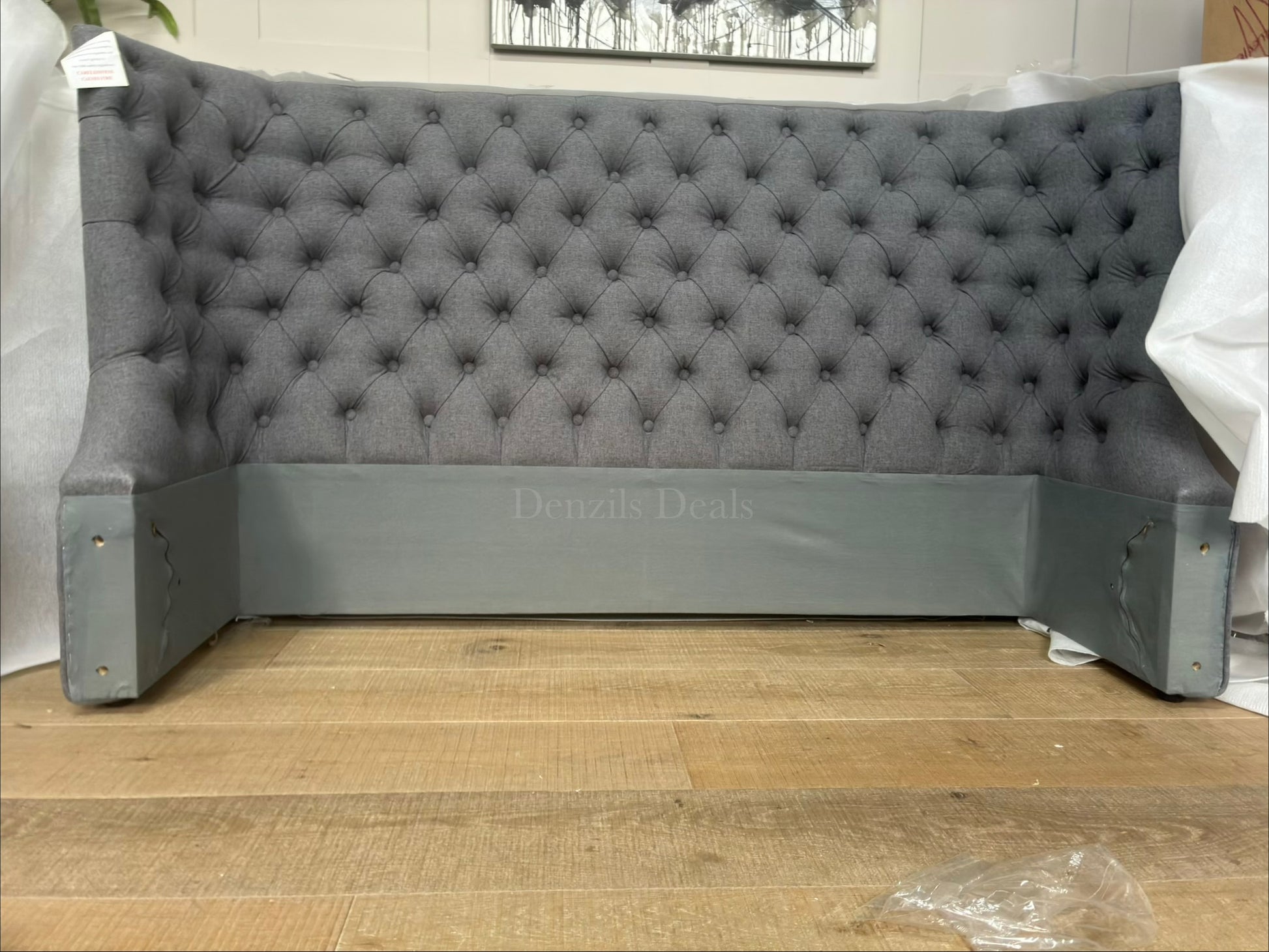 Elegant king size ottoman bed upholstered in grey fabric with a traditional buttoned headboard. Close up view on headboard 