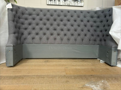 Elegant king size ottoman bed upholstered in grey fabric with a traditional buttoned headboard. Close up view on headboard 