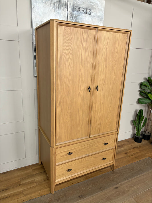 Freestanding John Lewis Bevel Double Wardrobe in a natural light oak finish, featuring two hinged doors with minimalist metal handles, two spacious storage drawers at the base, and distinctive beveled detailing along the edges and plinth.
