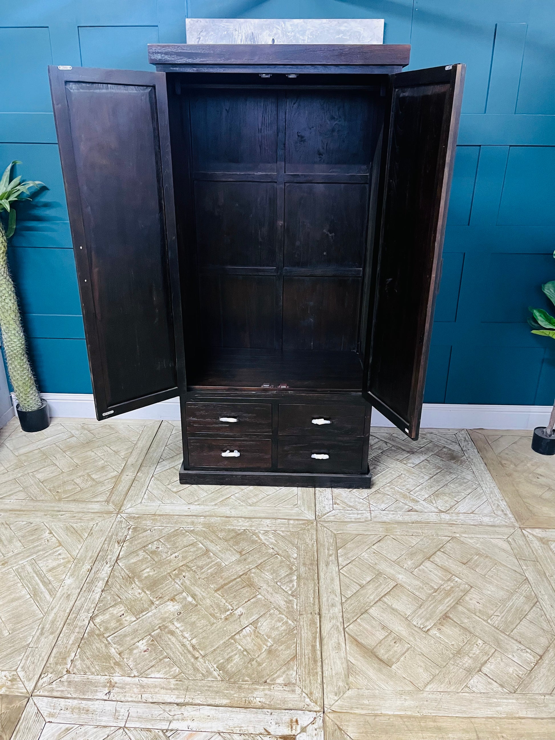 Freestanding Puji wardrobe crafted from solid natural teak wood. The piece features two large, hinged cabinet doors that open to full hanging space, set above three wide, horizontally aligned drawers at the base, and displays a prominent, rich grain finish