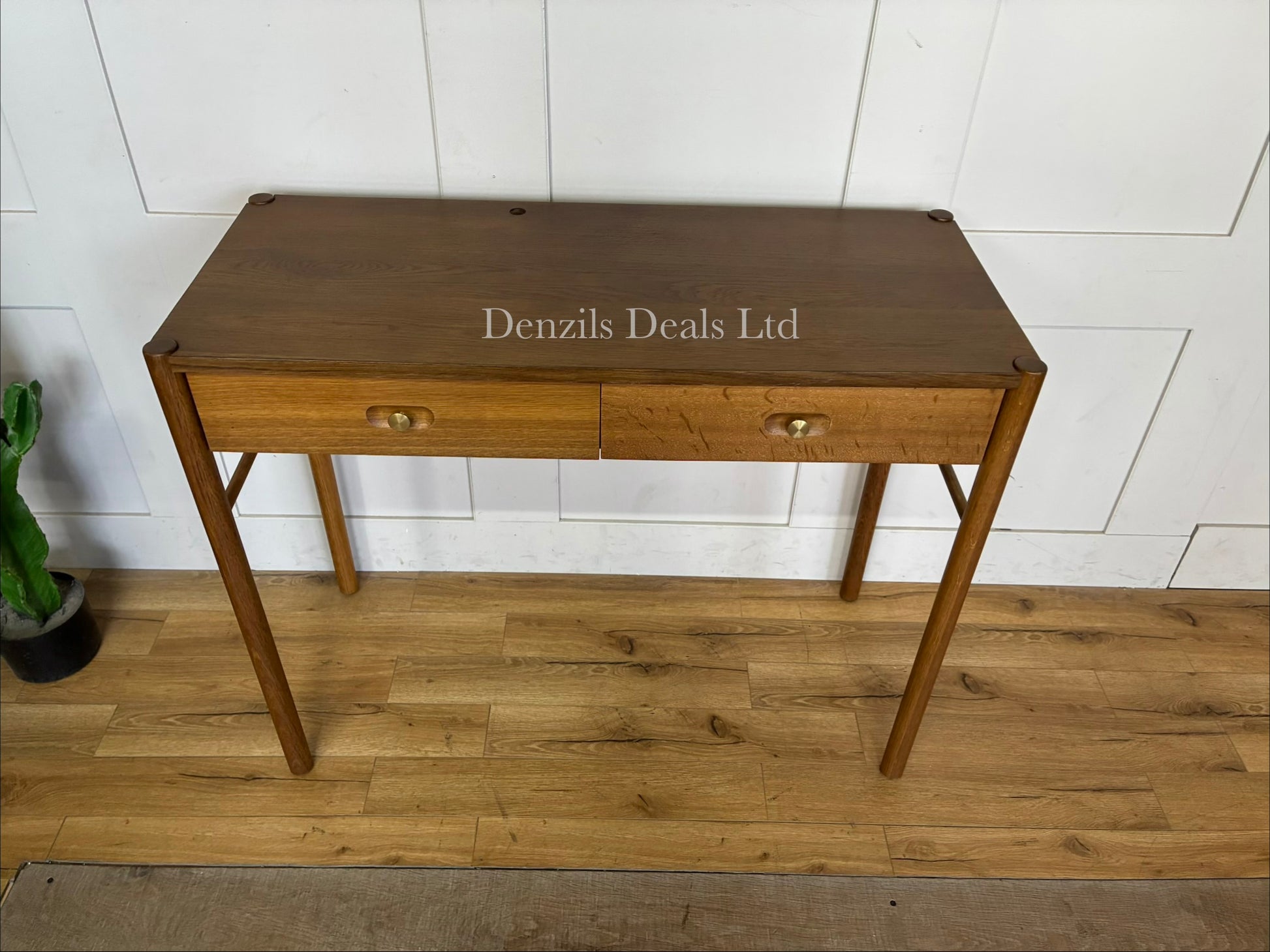 Front view of the Anthropologie Bernadette Makeup Vanity. The compact dressing table features a light oak finish, two storage drawers on wooden glides, and modern brass knobs, styled in a minimalist bedroom."