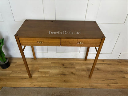 Front view of the Anthropologie Bernadette Makeup Vanity. The compact dressing table features a light oak finish, two storage drawers on wooden glides, and modern brass knobs, styled in a minimalist bedroom."