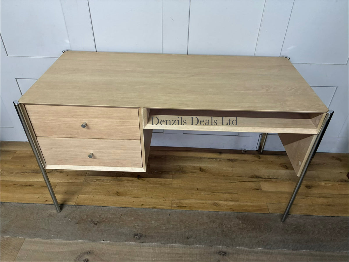 Front view of the John Lewis Hansen 2-drawer desk in a natural light oak finish. The desk has a minimalist, contemporary design with a smooth rectangular tabletop. Directly beneath the surface are two wide drawers sitting flush against the frame, separated by a slim central partition. Below the drawers is a full-width open storage shelf. The entire unit is supported by four slender, square legs crafted from matching solid oak wood.