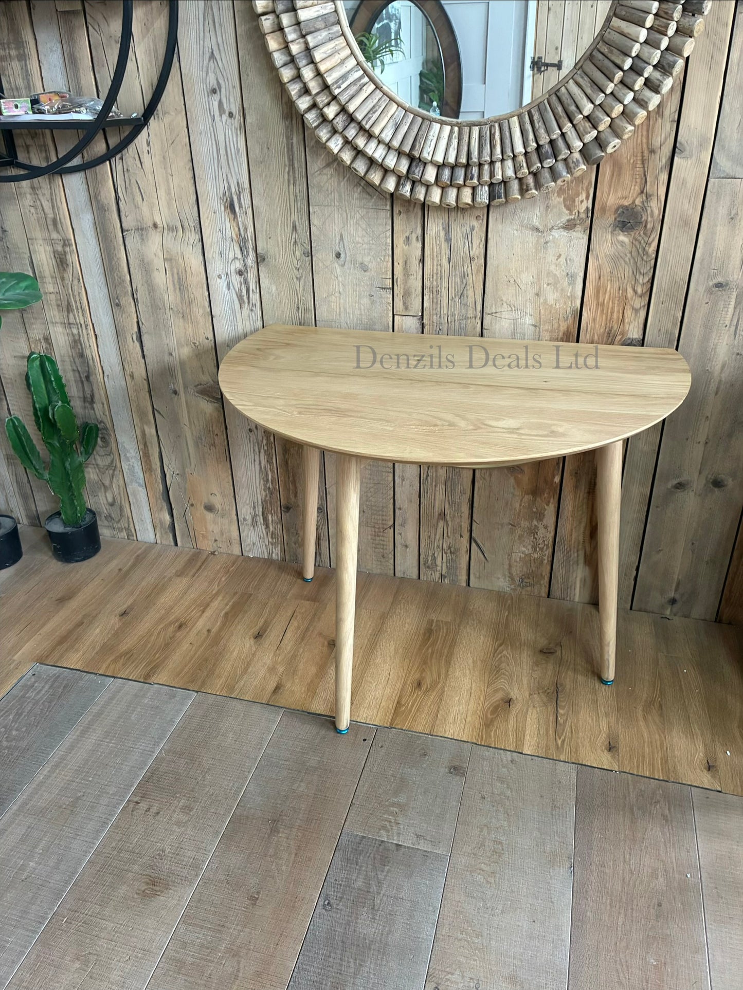 Gallery Direct Lewes oak dining table shown with its side leaves folded down vertically for compact, space-saving storage against a wall.