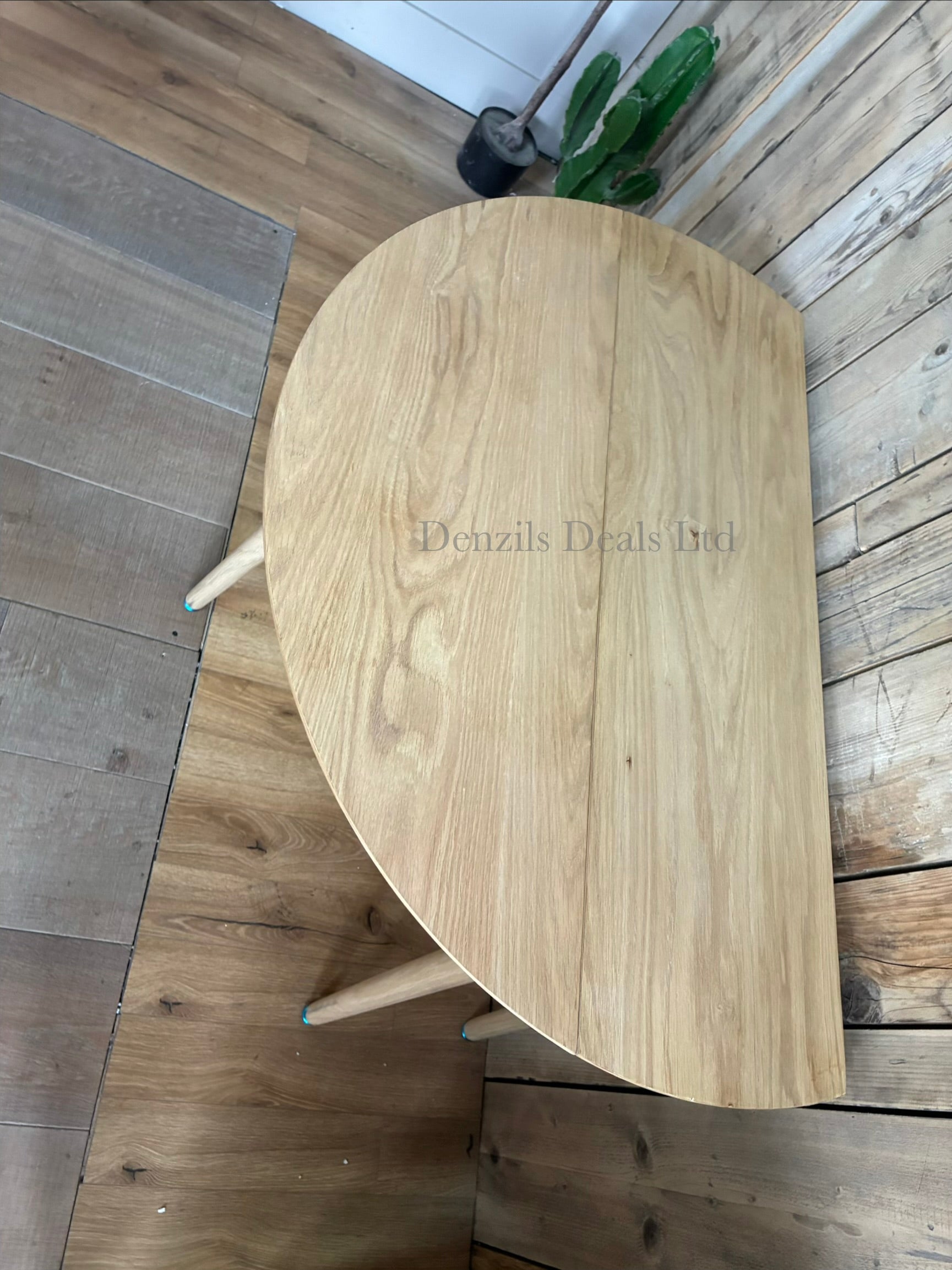 Gallery Direct Lewes oak dining table shown with its side leaves folded down vertically for compact, space-saving storage against a wall.