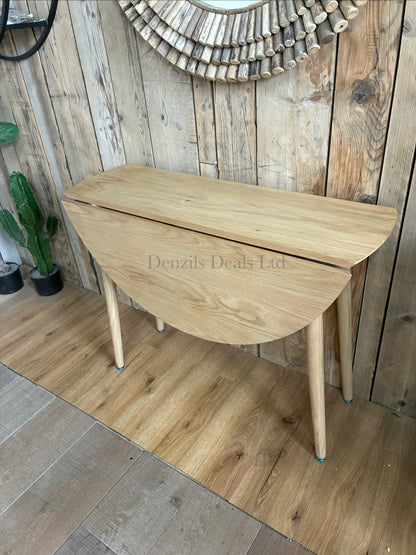 Space-saving Gallery Direct Lewes round dining table made of light natural oak, shown fully extended to seat four people.