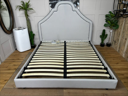 Handmade Joules Thornton super king bed frame in blue, featuring a towering oversized headboard, classic turned dark-wood feet, and all-over heritage upholstery